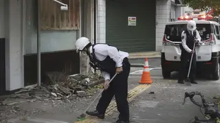 Police officers clean the debris from an earthquake in Uwajima, Ehime prefecture, western Japan