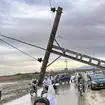 People pass by a damaged electric pole caused by flooding due to heavy rains in Pakistan