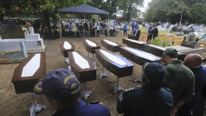 Authorities stand next to the nine coffins that contain the remains of unidentified migrants, at the Sao Jorge cemetery, in Belem, Para state, Brazil