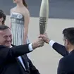 Tony Estanguet, president of Paris 2024, right, receives the Olympic flame from Spyros Capralos, head of Greece’s Olympic Committee, during the flame handover ceremony at Panathenaic stadium, where th
