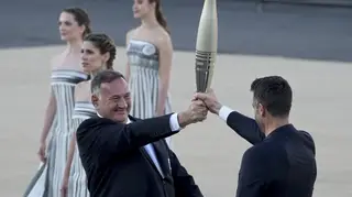 Tony Estanguet, president of Paris 2024, right, receives the Olympic flame from Spyros Capralos, head of Greece’s Olympic Committee, during the flame handover ceremony at Panathenaic stadium, where th