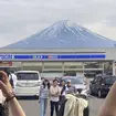 Visitors take a photo of Mount Fuji in front of a store