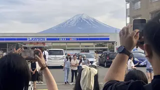 Visitors take a photo of Mount Fuji in front of a store