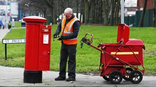 A postman collects mail from a postbox