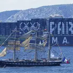 The Belem, the three-masted sailing ship bringing the Olympic flame from Greece, sails past a container ship decorated with the Paris 2024 logo when approaching Marseille, southern France