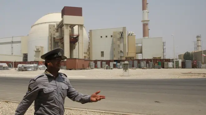 An Iranian security official directs media at the Bushehr nuclear power plant.