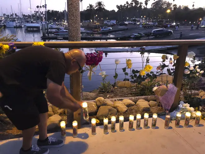 A man adds to the growing memorial for victims