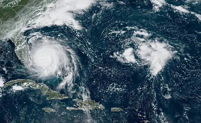 This GOES-16 satellite image taken Monday, Sept. 2, 2019, at 16:40 UTC and provided by National Oceanic and Atmospheric Administration (NOAA), shows Hurricane Dorian, left, churning over Bahamas.