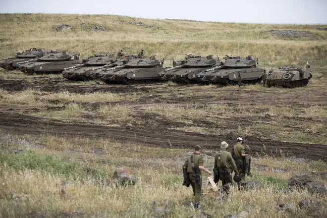 Israeli soldiers walk past tanks in the Israeli-controlled Golan Heights near the Syrian border.
