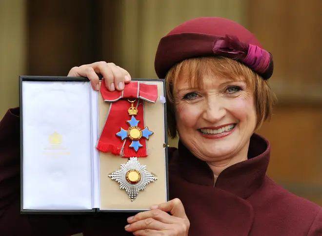 Dame Tessa Jowell proudly holding her Dame Commander insignia.