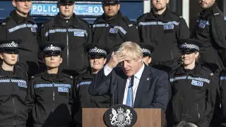 The Prime Minister addresses the nation with a backdrop of police officers