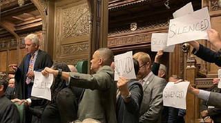 Opposition MPs hold up protest signs in Parliament