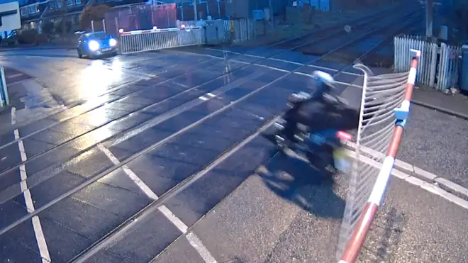 Moped riders risk their lives by speeding through a level crossing.