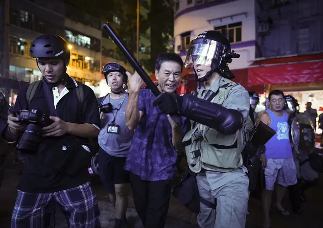 A Pro-China supporter is escorted by police after confronting journalists in Hong Kong.