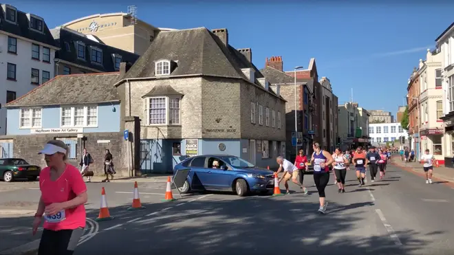 A man battles with the driver to stop her driving onto the marathon route