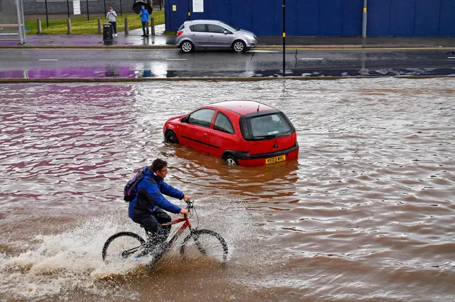 A man cycles past a stranded car on a flooded road in Birmingham city centre.