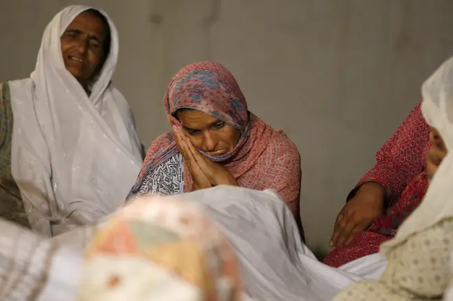 Women mourn beside the dead body of their family member who died in the earthquake