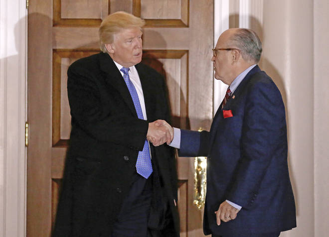 Former New York City Mayor Rudy Giuliani shakes hands with US President Donald Trump