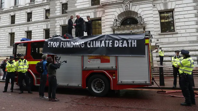 Extinction Rebellion climate activists stand on a fire engine outside the Treasury building in London after activists sprayed hundreds of litres of fake blood on the building