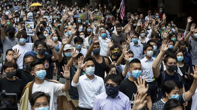 Protests against the face mask ban raise their hands to symbolise their five demands