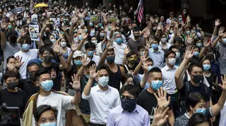 Protests against the face mask ban raise their hands to symbolise their five demands