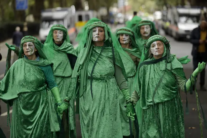 Green costumed Extinction Rebellion climate change demonstrators walk together in silent protest on Millbank in London.