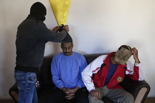 In 2018 a Kurdish security officer takes off face masks from Alexanda Amon Kotey, left, and El Shafee Elsheikh, who were allegedly among four British jihadis who made up a brutal Islamic State cell dubbed "The Beatles"