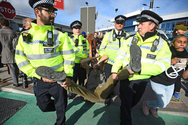A man is removed by police officers after activists staged a 'Hong Kong style' blockage of the exit from the train station to City Airport, London, during an Extinction Rebellion climate change protest.