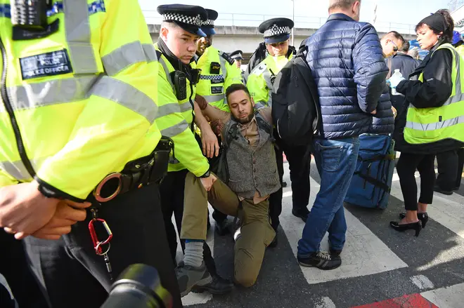 A man is removed by police officers after activists tried to block City Airport