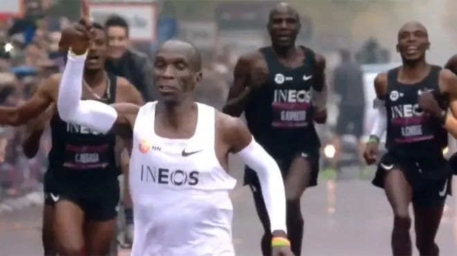 Eliud Kipchoge points to the crowd as he crosses the marathon finish line