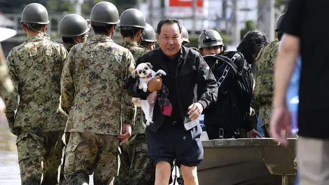 Troops walks past as a man rescues his dog in Motomiya, Fukushima prefecture