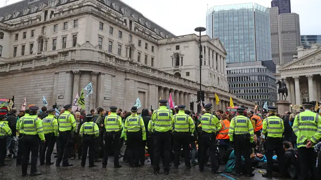 Police attempt to push back protesters as they continue to block the road outside Mansion House