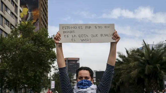 A demonstrator raises a sign that reads in Spanish "This is not for 30 pesos in fare, it's the drop that overflows the glass"