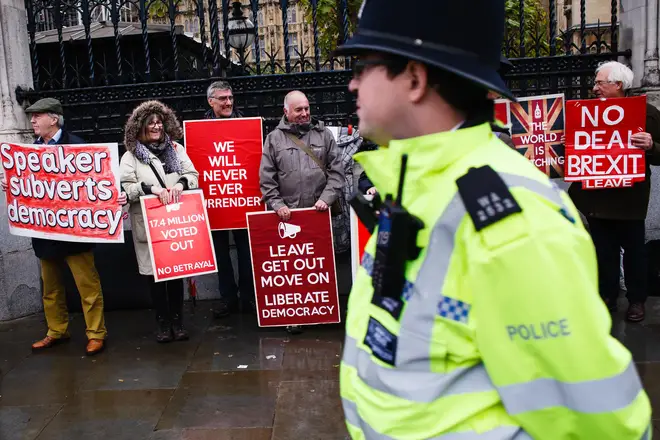 A police officer walks past pro-Brexit activists demonstrating outside the Houses of Parliament