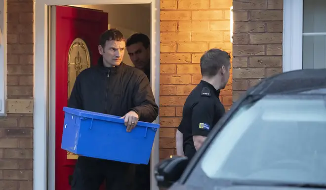 Police leave the home of a couple, both 38, with an evidence box at Wiltshire close in Warrington, Cheshire, after they were arrested on suspicion of manslaughter and conspiracy to traffic people