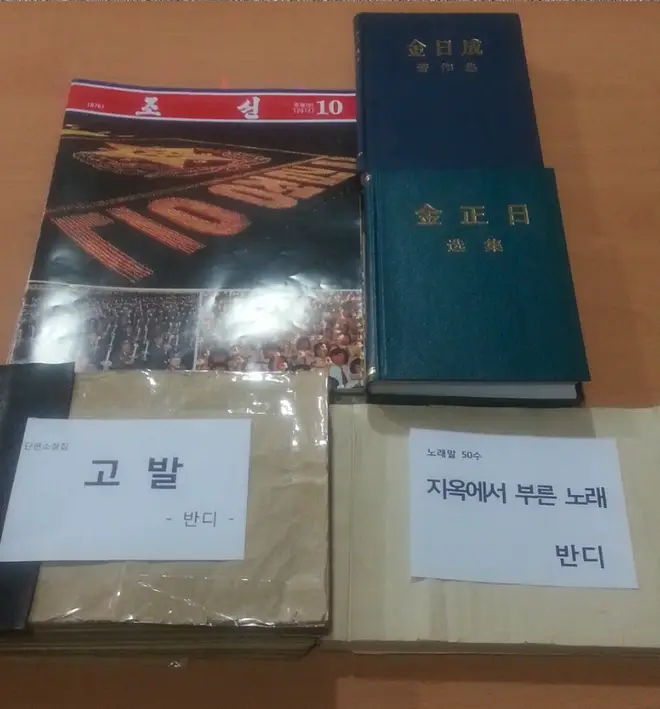 The manuscript (bottom) was smuggled by hiding it inside North Korean propaganda