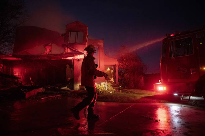A firefighter assesses the damage of a home in California