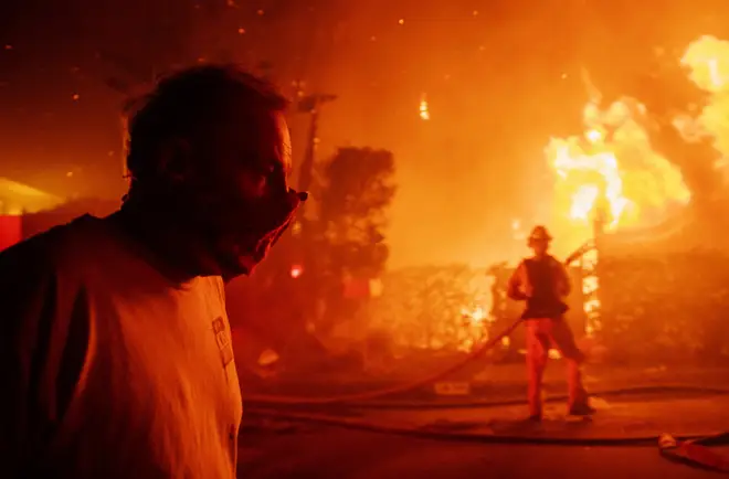 A man walks past a burning home