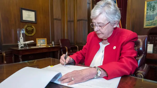 Alabama Governor Kay Ivey signing the bill to virtually outlaw abortion in the state