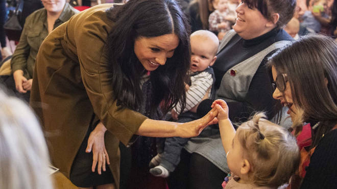 Meghan Markle high-fives one of the children at the coffee morning in Windsor