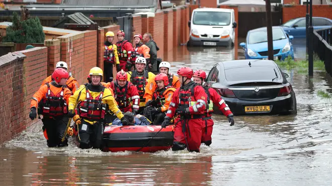 Fire and Rescue service members pull an inflatable boat that has been used to rescue residents trapped by floodwater in Doncaster