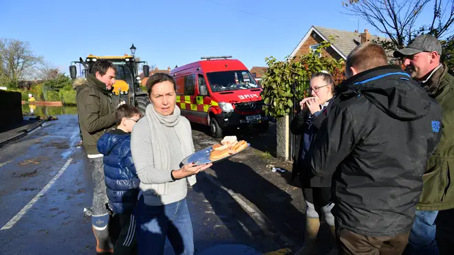 Helen Edwards hands out free bacon sandwiches to villagers in Fishlake, Doncaster as parts of England endured a month's worth of rain in 24 hours.