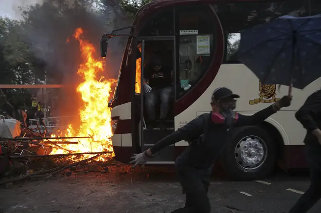Students run past fire set near a bus during a face-off with riot police at the Chinese University in Hong Kong