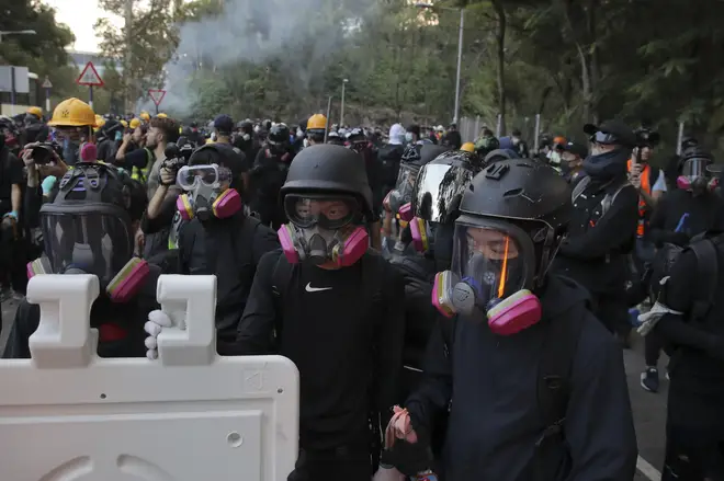 Students with gas masks stand watch behind barricades after a faced-off with riot police at the Chinese University in Hong Kong