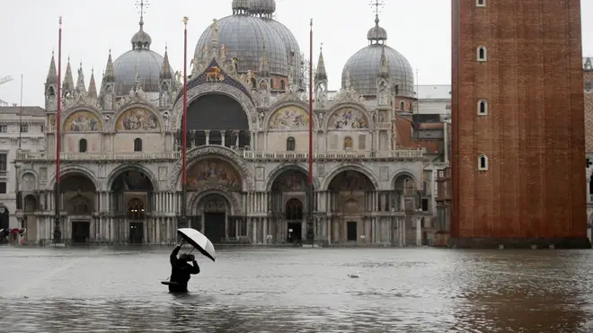 A member of the public wades through water outside St Mark's Basilica