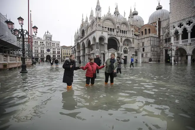 People wade through water in a flooded St. Mark's Square in Venice