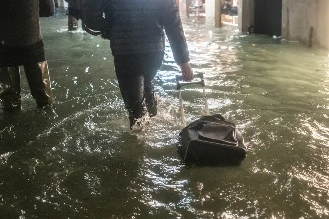 A tourist walks near a store after the exceptional high tide or 'Alta Acqua' that reached 190 cm at late night