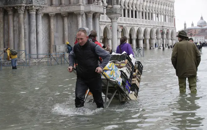 A greengrocer pulls his cart through high water in Venice