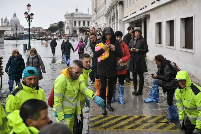 Volunteers set up a footbridge for pedestrians across the flooded Riva degli Schiavoni embankment
