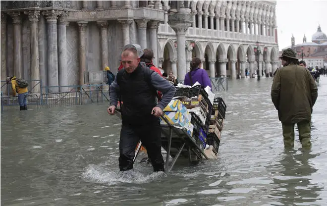 A greengrocer pulls his cart through high water in Venice